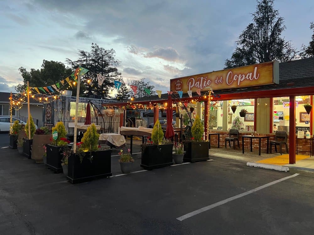 The patio at Patio Del Copal at dusk, strung with lights beneath a hand-painted sign